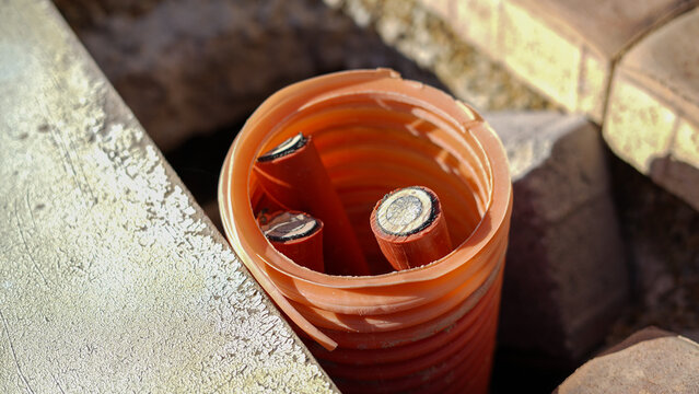 Electric cables inside orange protective conduit in construction site