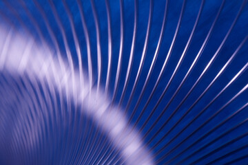 Macro texture of steel wire coil with radial arc pattern. Futuristic dark blue wallpaper with diagonal light reflection and geometric flow. Photo