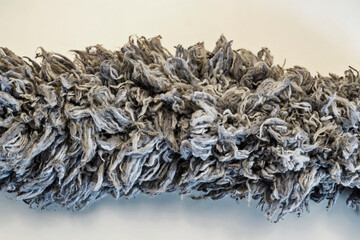 Detailed macro shot of a used gray microfiber duster, showing tangled and fuzzy fibers against a plain background. Ideal for cleaning, texture, and abstract concepts