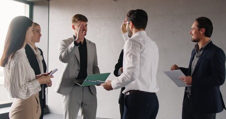 Diverse group of business people or colleagues celebrating success in an office, exchanging high fives, applauding, and fostering a sense of teamwork and camaraderie during a meeting.