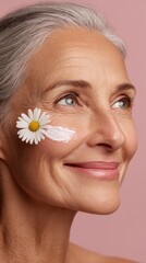 Portrait of an older woman with a daisy on her cheek against a pink backdrop
