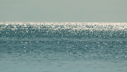Tranquil sea with sun glare and sparkling reflections on the water surface