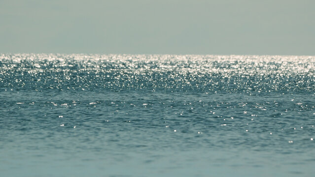 Tranquil sea with sun glare and sparkling reflections on the water surface