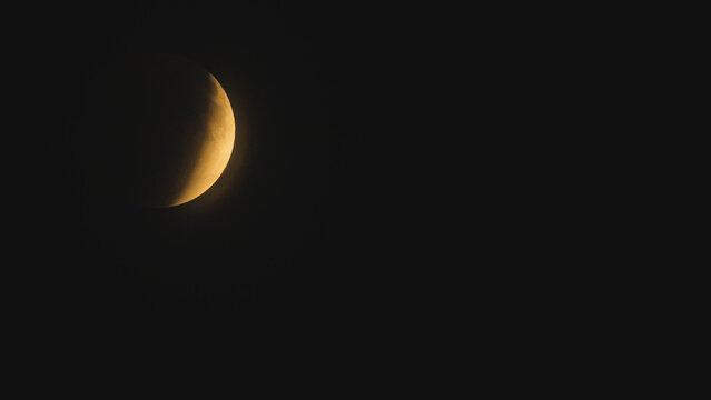 Partial lunar eclipse with golden crescent moon against a black sky - Powered by Adobe