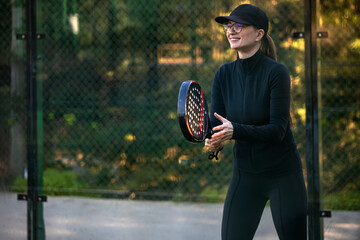 Woman Padel tennis player with racket in action on the court. Girl athlete with paddle racket on...
