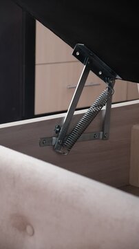 Spring loaded lift mechanism on bed, sofa with storage compartment. Upholstered furniture 