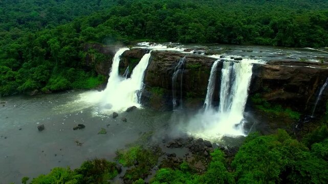 Majestic Athirappilly waterfalls cascade down rocky cliffs surrounded by lush green rainforest in India