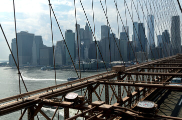 Obraz premium The Brooklyn Bridge, built in 1883, is the first suspension bridge constructed of steel and overlooks the skyscrapers of Manhattan, the Big Apple.