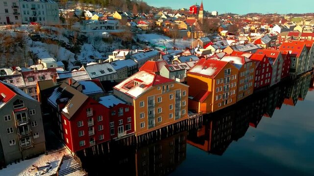 Colorful historic waterfront buildings reflected in calm water during a snowy winter day