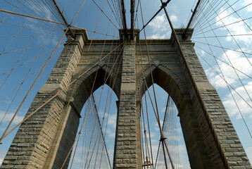 Fototapeta premium The Brooklyn Bridge, built in 1883, is the first suspension bridge constructed of steel and overlooks the skyscrapers of Manhattan, the Big Apple.