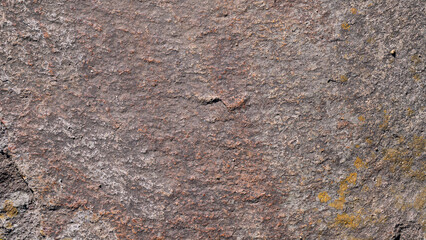 オレンジ色の地衣類が付着した荒い岩肌のクローズアップ背景