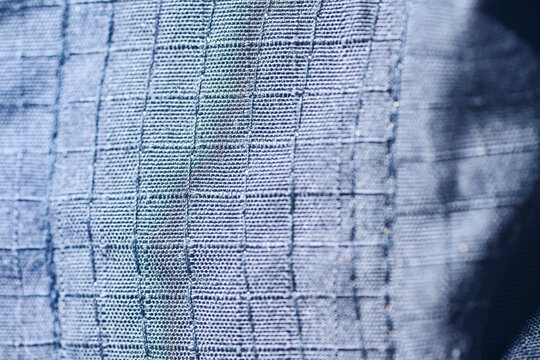 Detailed macro shot showcasing the intricate grid weave and texture of a durable blue ripstop fabric, commonly used in outdoor gear and tactical equipment