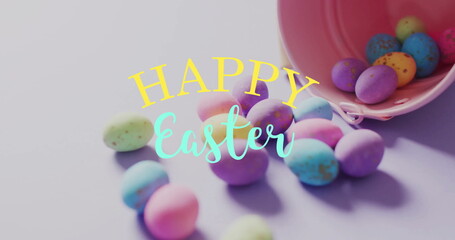 Image of happy easter text over colourful easter eggs and pink bucket on purple background