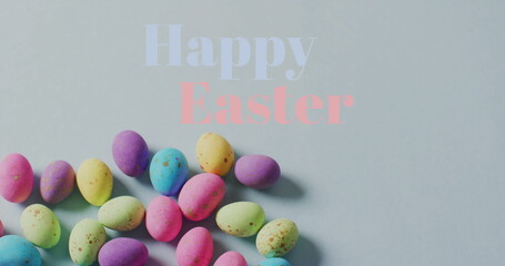 Image of happy easter text over colourful easter eggs on grey background