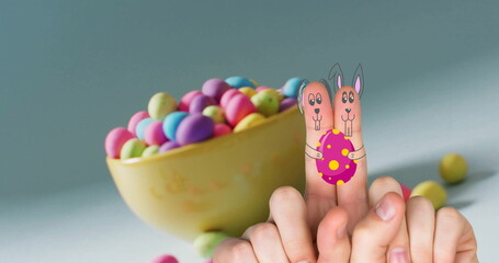 Image of fingers with easter bunny faces and easter eggs on blue background