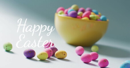 Image of happy easter text over colourful easter eggs in bowl on blue background