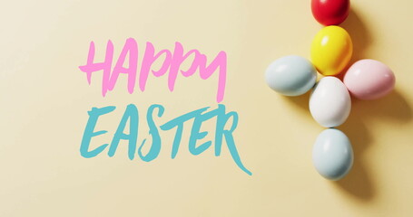 Image of happy easter text over colourful easter eggs on yellow background