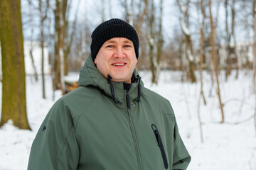 Portrait of a middle aged man. Mature man, 40 or 45 years old, takes a walk in a winter forest.