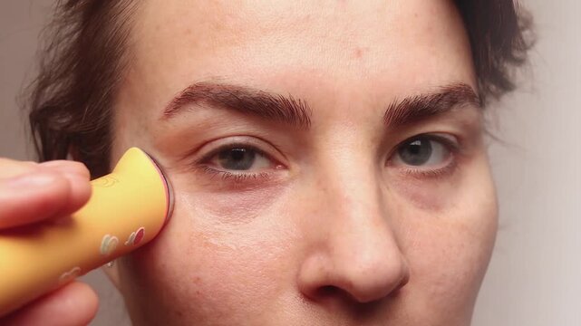 Close up crop footage of Caucasian woman using microcurrent facial toning device at home. Beauty popular device for muscles contract 4k