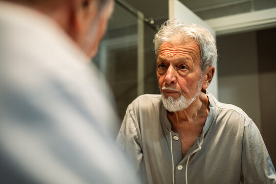 Senior man looking at his reflection in bathroom mirror