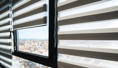 Modern zebra roller blinds on large apartment window with city skyline view, contemporary interior design and natural daylight © Volodymyr_sh