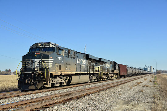Two run-through Norfolk Southern Railway locomotives power a long crude oil unit train on Burlington Northern Santa Fe tracks while passing through a small north central Illinois community.