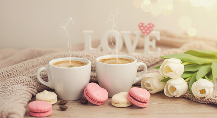 Two cups of coffee with macarons and flowers on table  