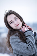 Snow Queen. A young girl in a white dress in the snow. Girl in a white dress. Bride. Winter cold weather. Model. Young woman in winter park.