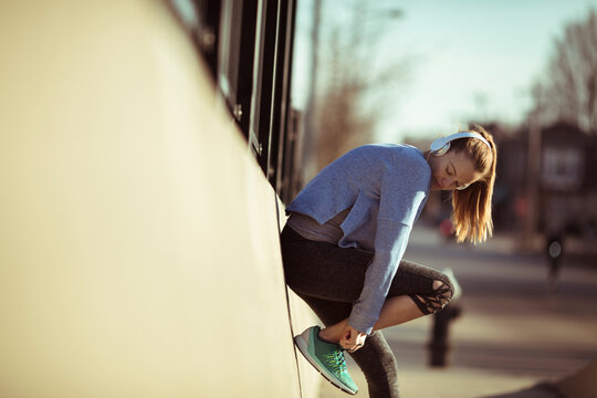 Woman runner tying shoe on urban street