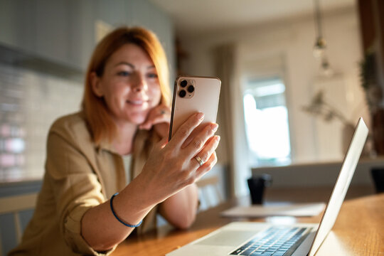 Smiling woman making video call on smartphone at home