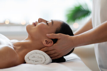 Relaxing head massage techniques concept. Woman enjoying rejuvenating full body massage in spa salon, profile side view, closeup