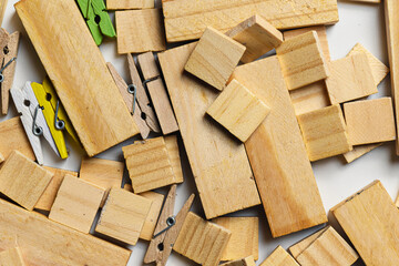 Top-down view of scattered wooden blocks in various sizes and shapes mixed with small colorful and natural wood clothespins. Ideal for craft, hobby, and DIY project concepts