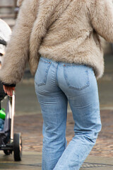 Back view of a person dressed in modern street wear including a fluffy fur jacket and straight leg denim jeans