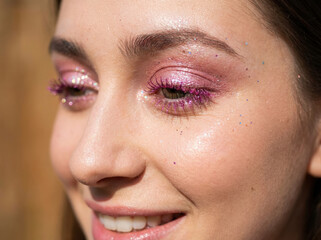 Close up portrait of a woman with a pink glittery trendy makeup 