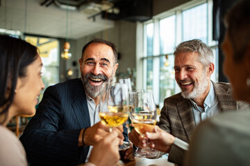 Smiling business colleagues toasting with white wine in restaurant
