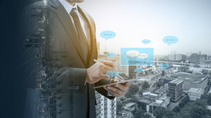 Professional businessman in a suit using a digital tablet for customer feedback, featuring speech bubble icons and a double exposure cityscape background for modern business concepts
