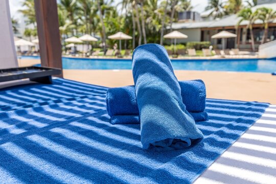 Luxury blue towels by swimming pool at tropical hotel resort, summer vacation background