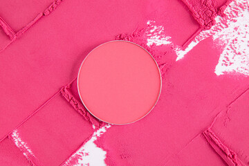 Round block, a refill of pink blush stands on a chic background with a pattern of bright dry blush. top view. Template for advertising cosmetics.