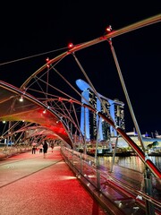 Obraz premium Illuminated bridge over marina bay, Vibrant nighttime scene featuring illuminated bridge and bustling waterfront promenade