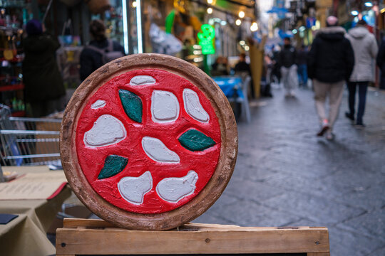 In the historic center of Naples, a drawing of a pizza on wood