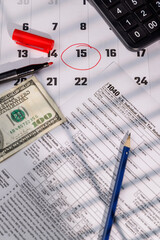 US Tax Day April 15 deadline marked on a calendar with IRS Form 1040 and a hundred dollar bill for professional business visuals.
