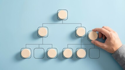 Hand arranging wooden blocks on an organization chart diagram to illustrate office structure and hierarchy.