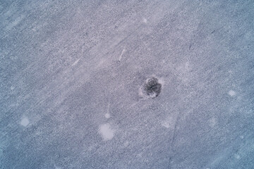 Obraz premium Solitary tree standing in a frozen agricultural field covered with hoarfrost illustrating loneliness and resilience concepts Aerial top down view