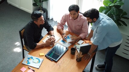 Top view of skilled project manager talking about financial graph to investors while sitting at meeting table with data analysis document. Diverse team discussing and brainstorming idea. Convocation.