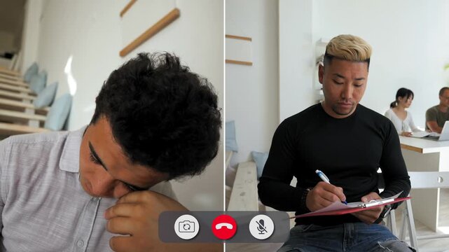 A man attends an online call while showing boredom. He sits in a simple room, looking away and taking notes, while another person is present in the background.