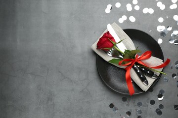Beautiful table setting with rose and confetti on grey background, flat lay. Space for text