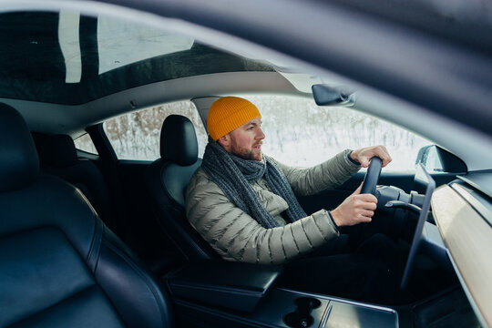 Male driver operating electric car in winter