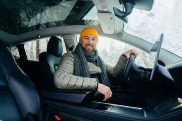Smiling man driving electric car in winter