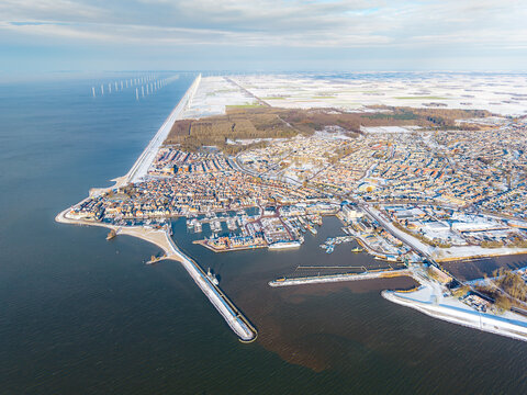 Aerial panorama of Dutch harbor town in winter with offshore wind farm