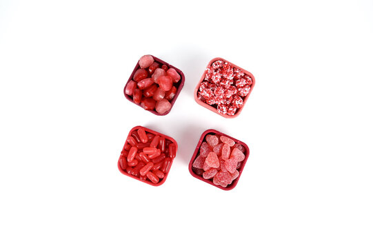 Valentine themed red and pink candy in pink and red silicon containers on white background